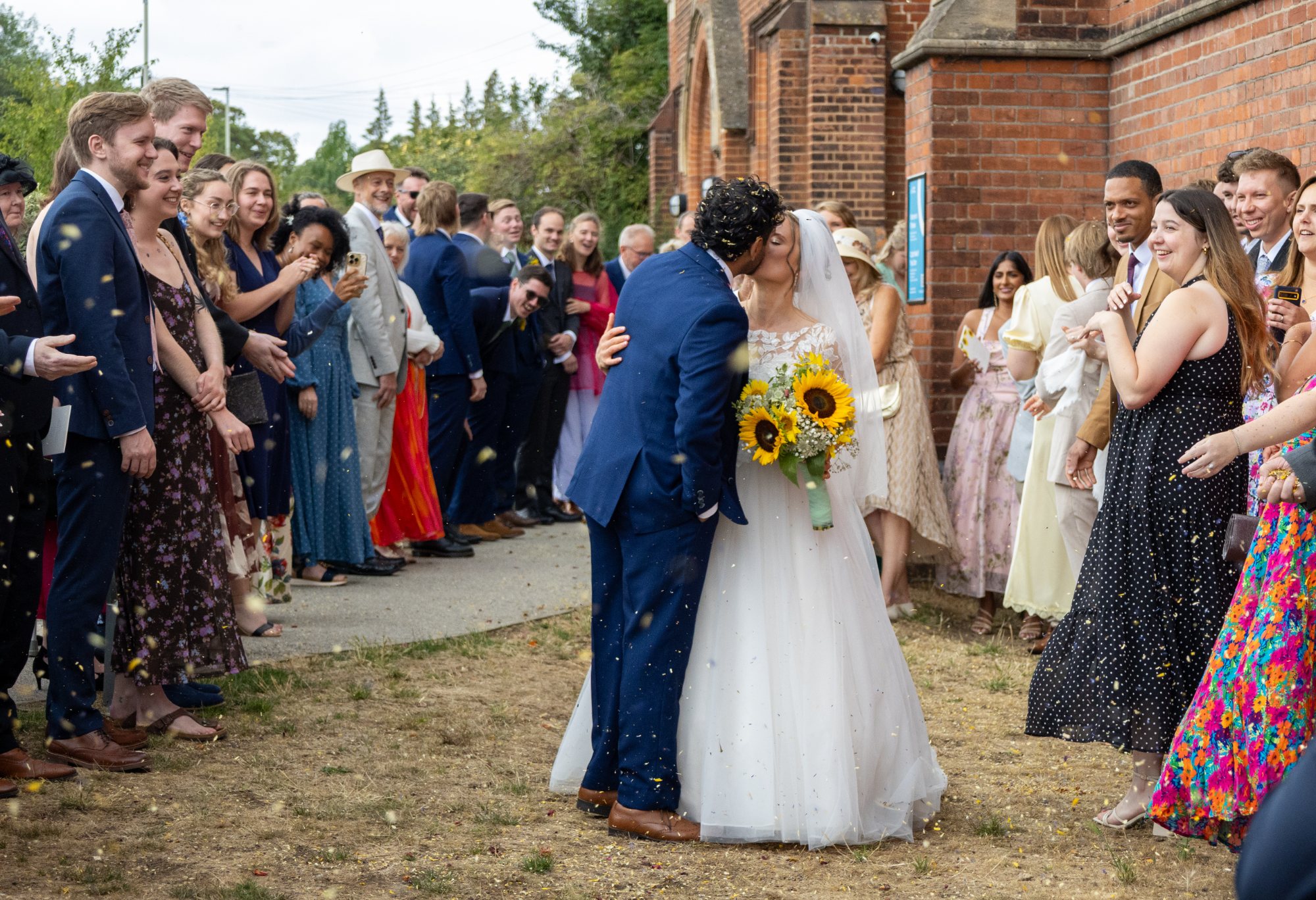 Katherine and Gurpreet kiss under a shower of confetti outside the church