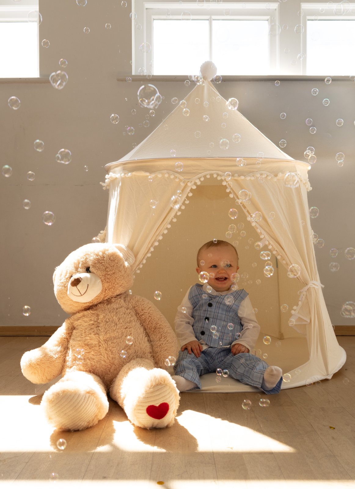 Baby in a play tent with bubbles and a teddy